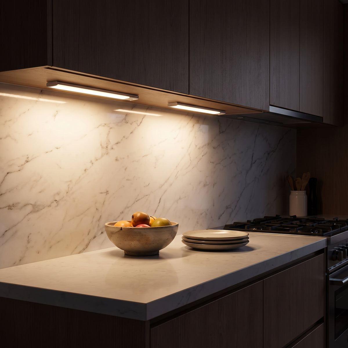 Under-cabinet bars casting warm light over a marble backsplash at night