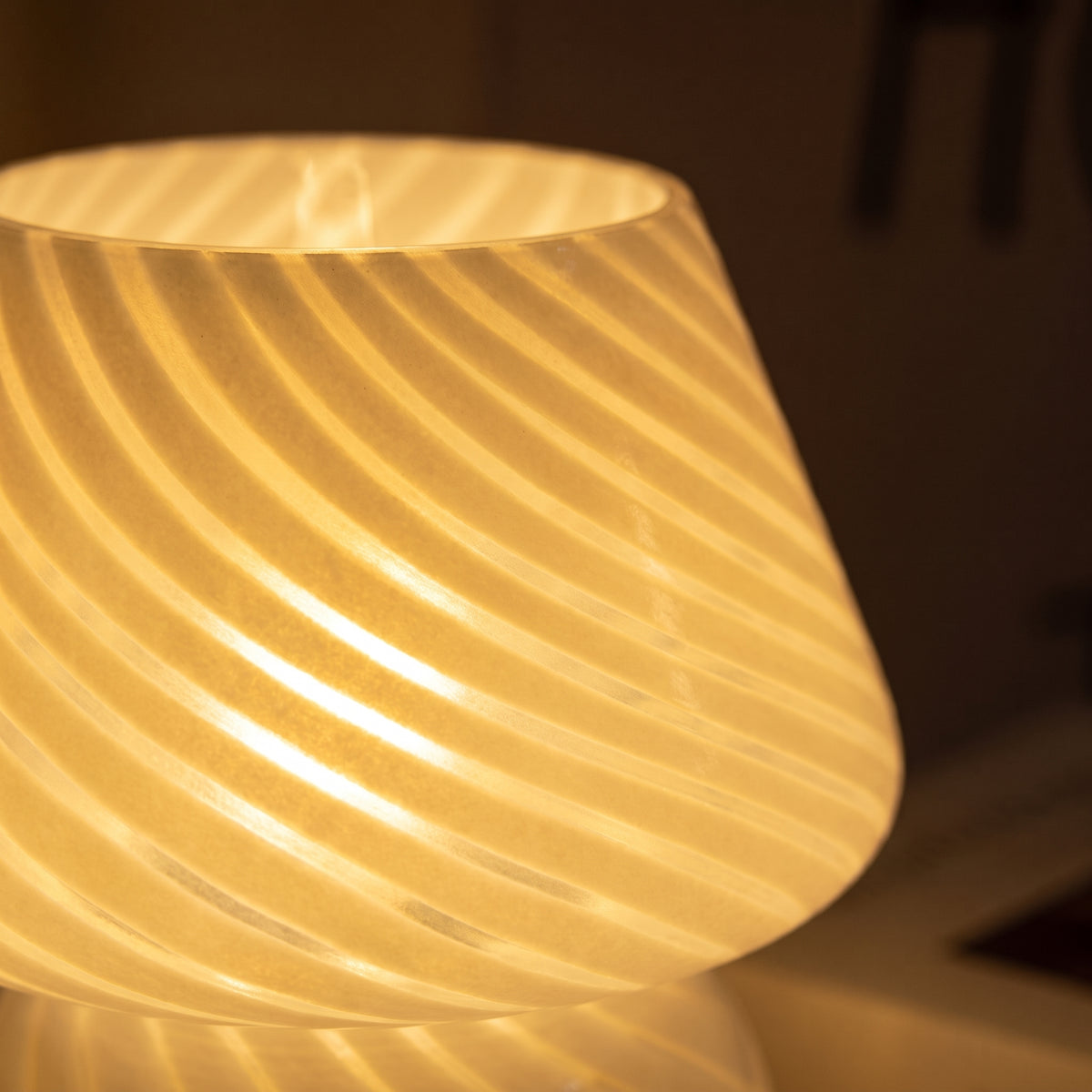 Close-up of the mushroom lamp lit — warm glow through the swirl-ribbed frosted glass