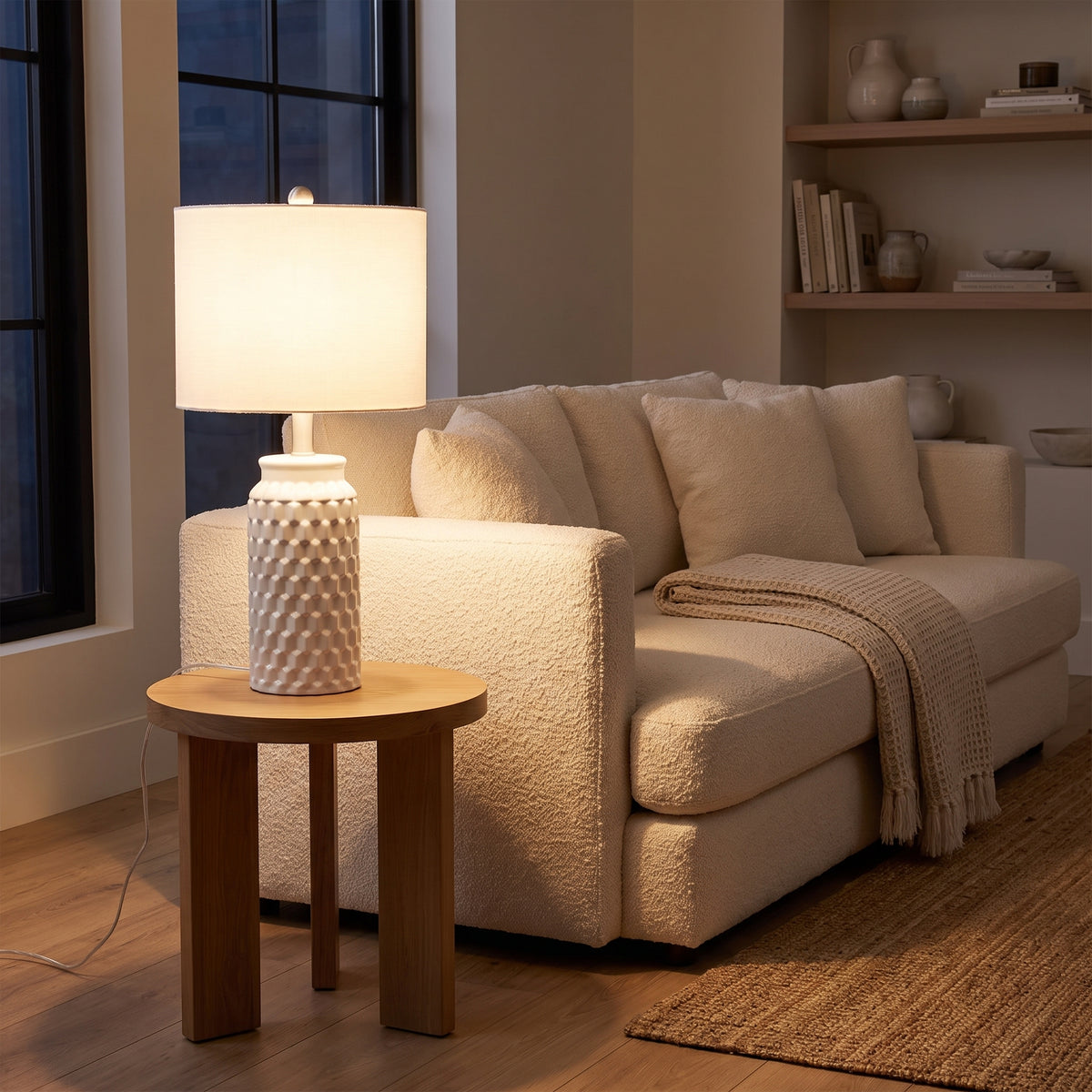 Ceramic table lamp beside a boucle sofa in a cozy evening living room