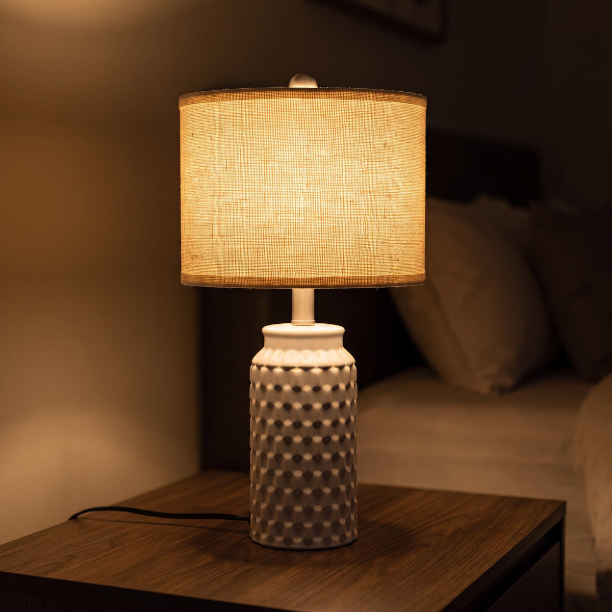 Linen shade of the ceramic lamp glowing warm in the dark, weave visible