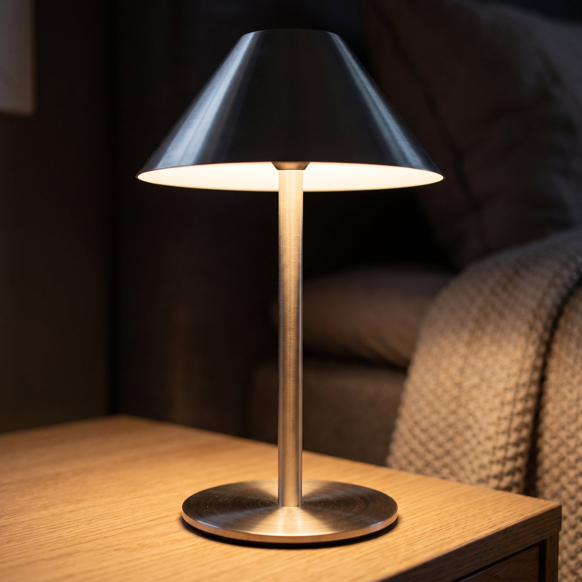 Warm light spilling from under the conical shade of the metal lamp at night