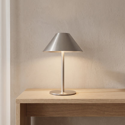 Brushed metal bedside lamp glowing softly on a light oak console