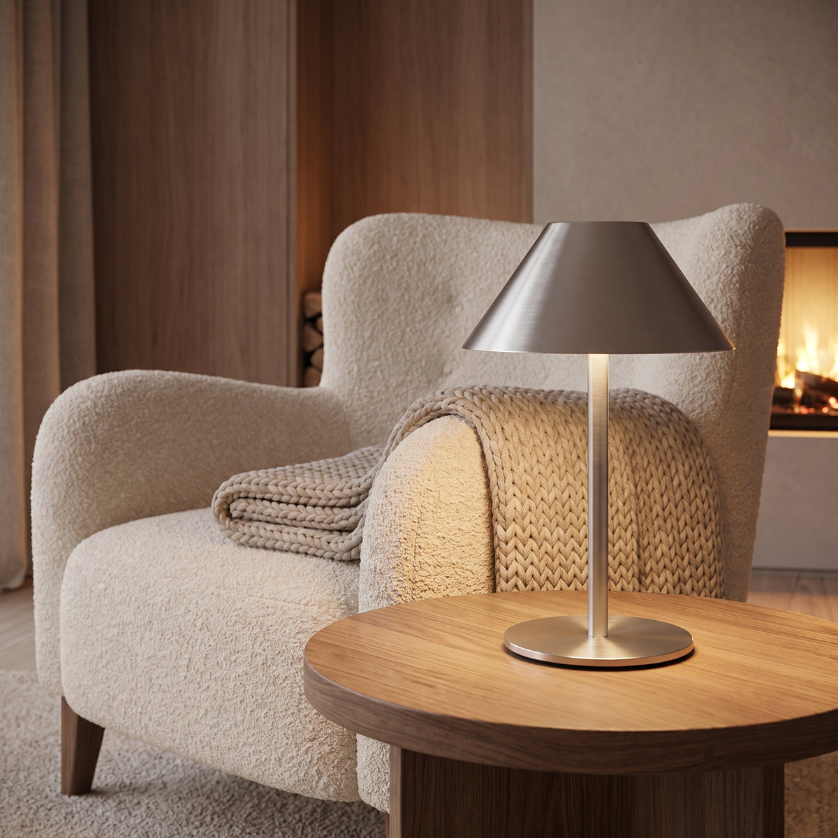 Metal lamp glowing on a side table beside a boucle armchair by the fireplace
