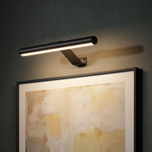 Rechargeable picture light switched on above a framed abstract painting on a dark green wall