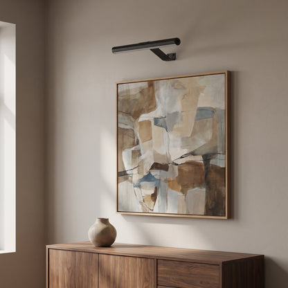 Picture light mounted above a framed abstract painting over a walnut sideboard