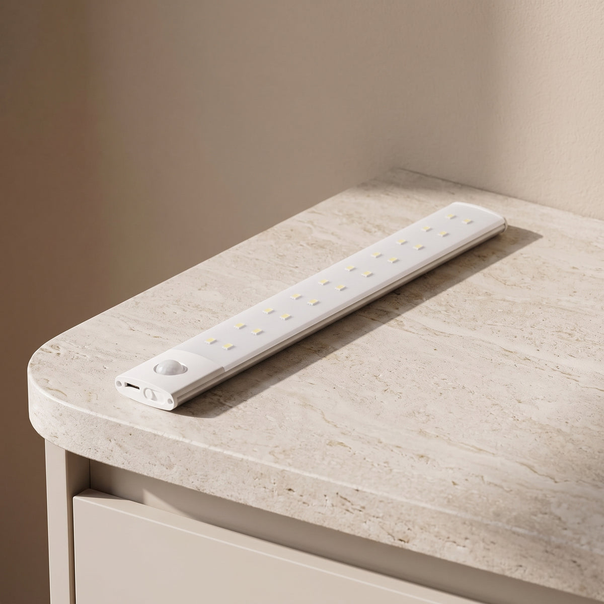 Slim white rechargeable light bar switched off on a stone countertop