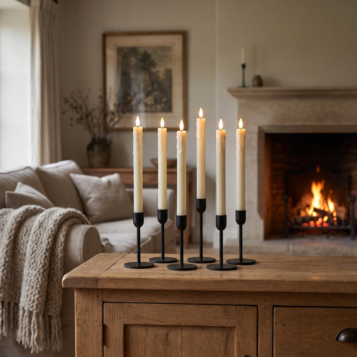 Six flameless LED taper candles in black holders on an oak sideboard, fireplace glowing behind