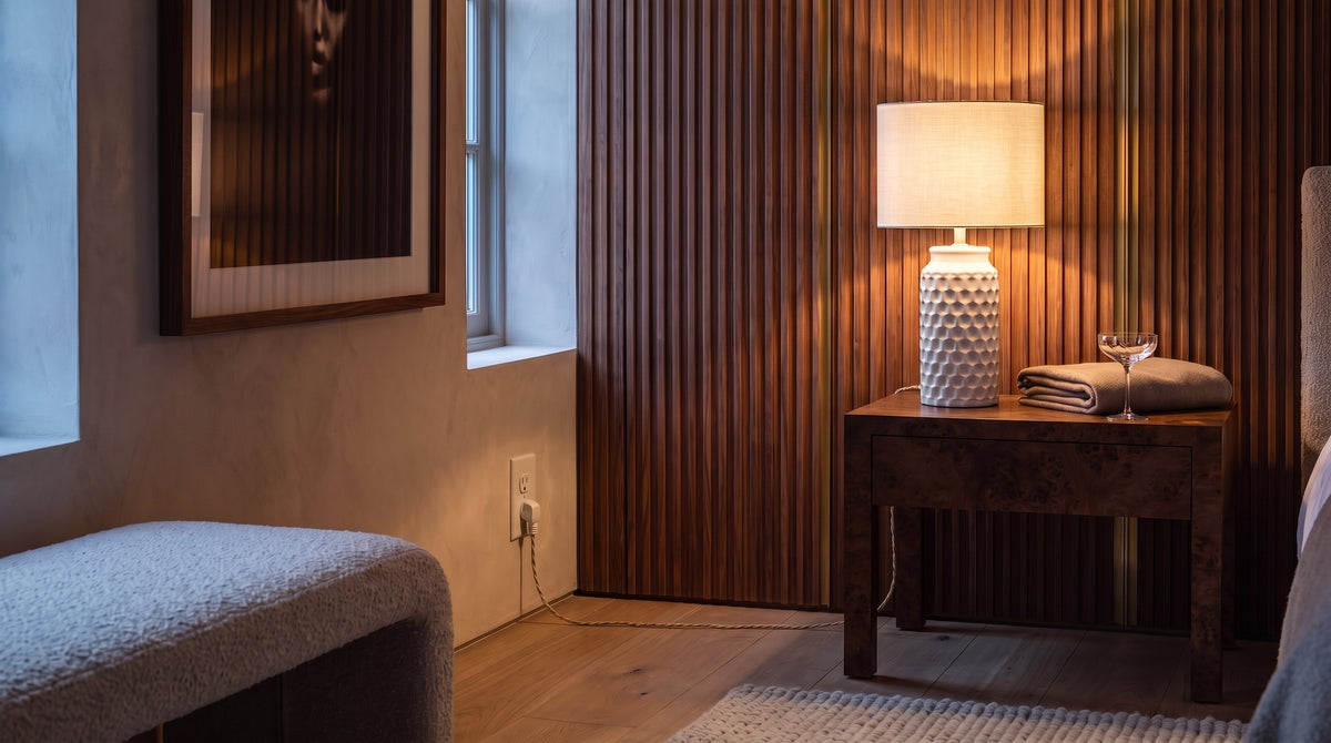 Ceramic table lamp with linen shade on a burl wood nightstand in a walnut panelled room